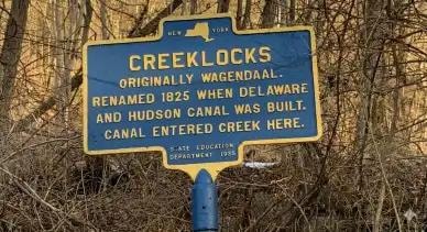 Historical marker sign reading: Creeklocks — Originally Wagendaal, renamed 1825 when Delaware and Hudson Canal was built. Canal entered creek here. State Education Department 1932.