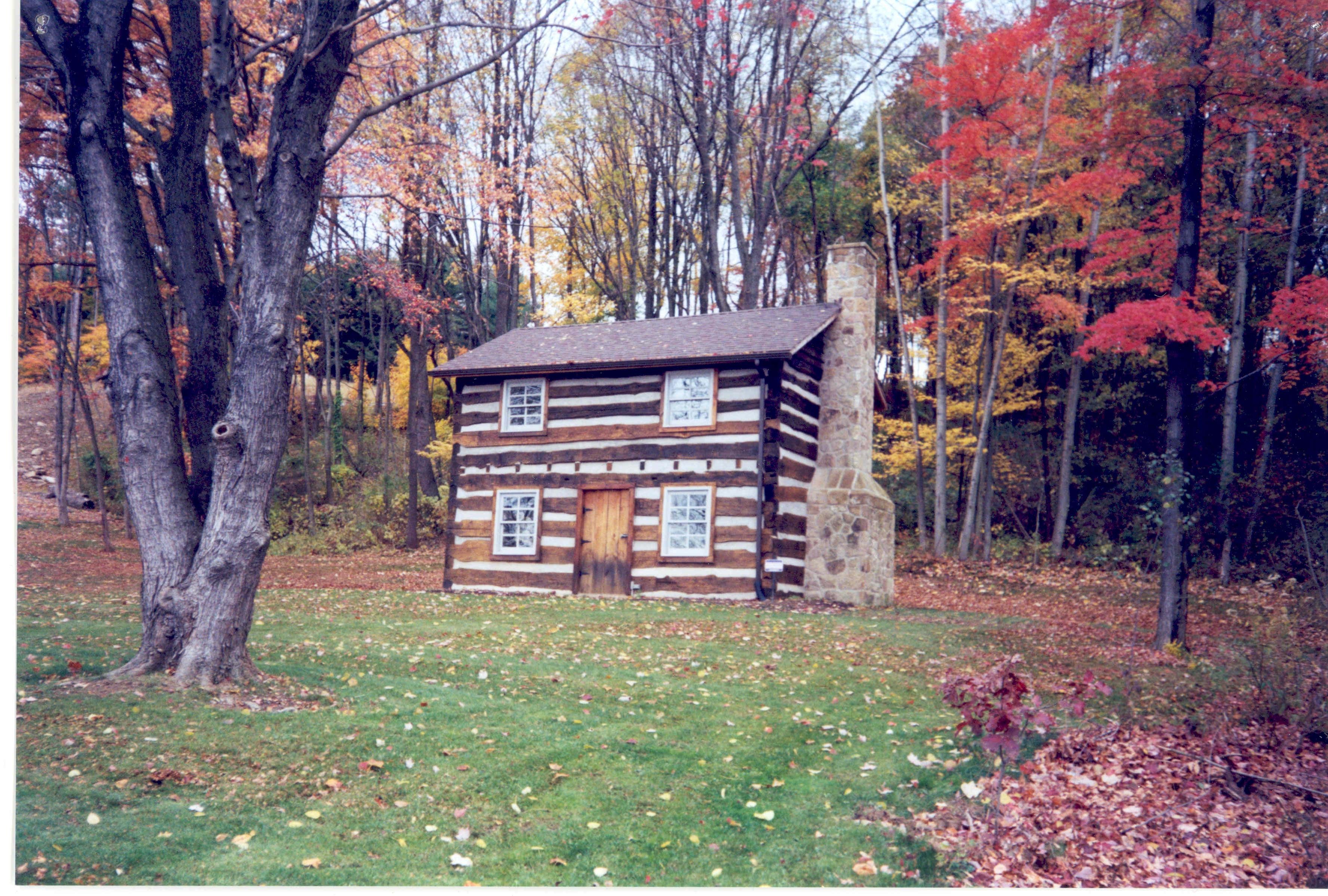 William Jones Log House, Franklin Park PA — a historic two-story log cabin with stone chimney surrounded by autumn foliage